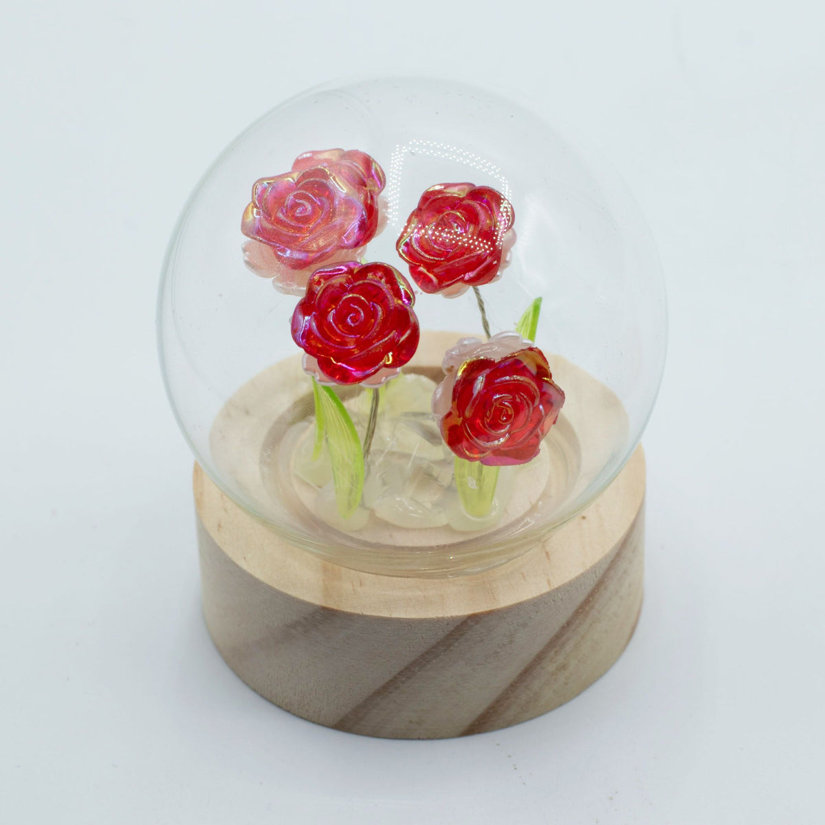 Floral Glow Garden Dome with red roses inside a clear glass dome on a pale wooden base, front view