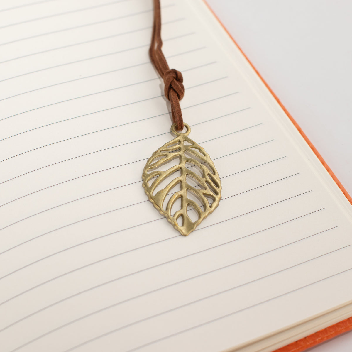 Leaf-shaped bookmark resting on lined notebook pages