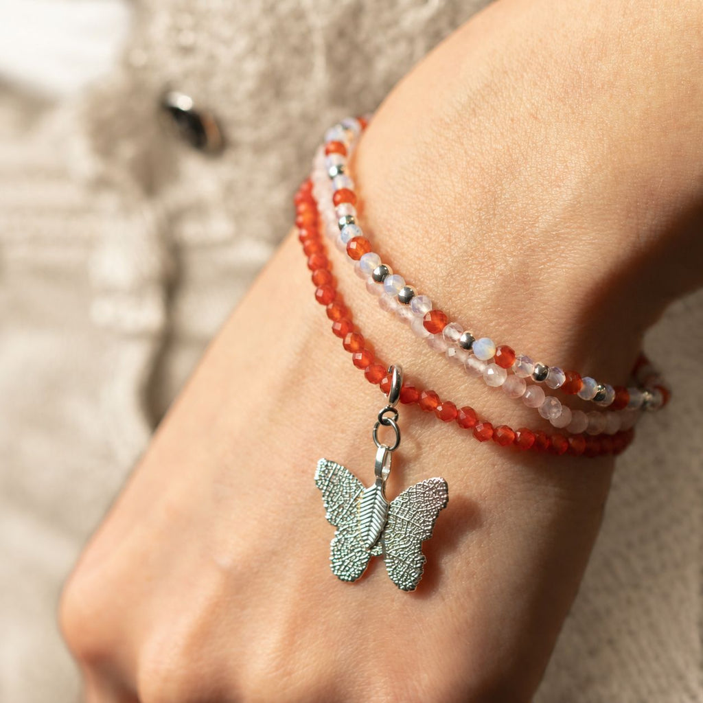 Angled view of the bracelets and butterfly charm on a wrist