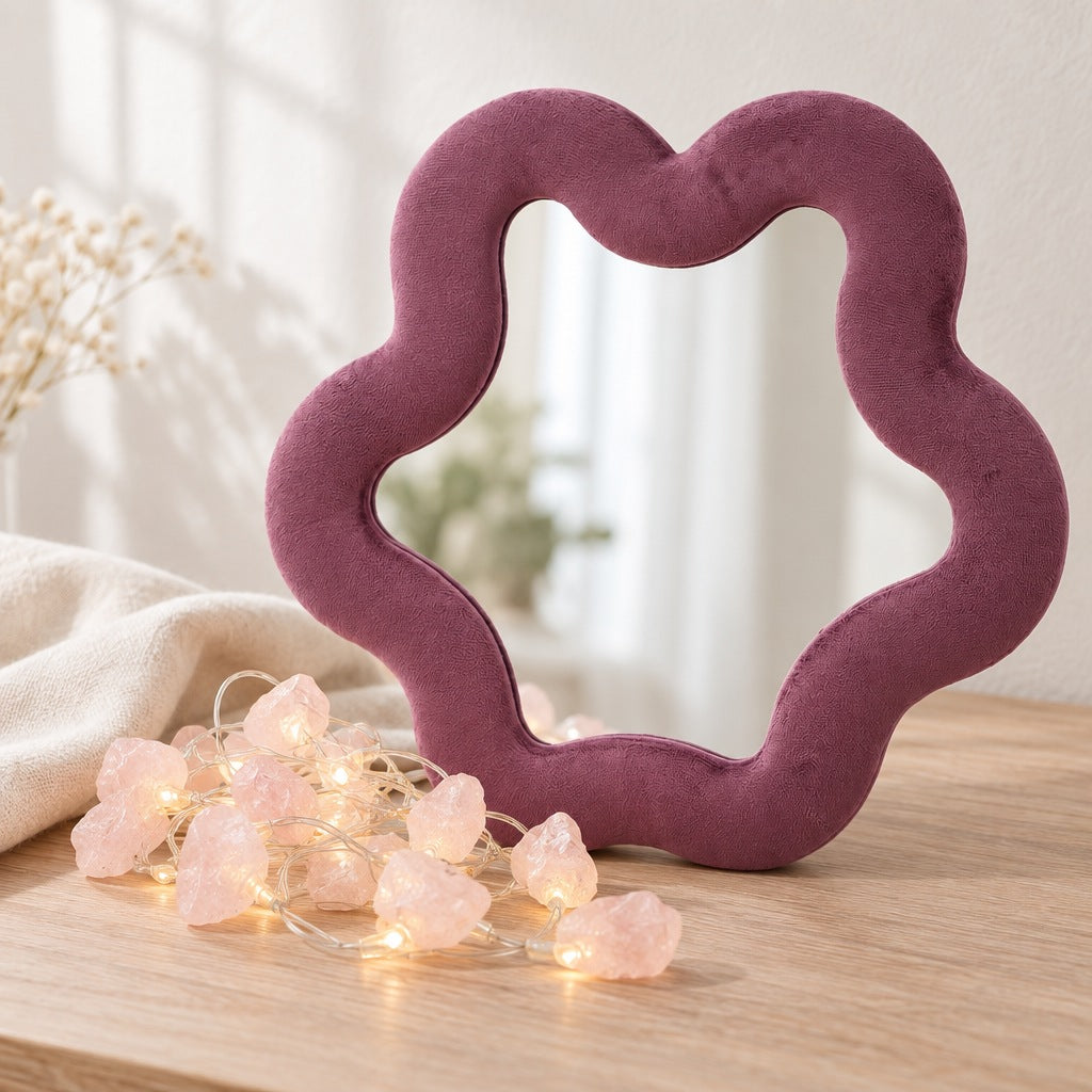 Mauve velvet star-shaped mirror standing on a desk with a string of lit rose quartz stone lights in front
